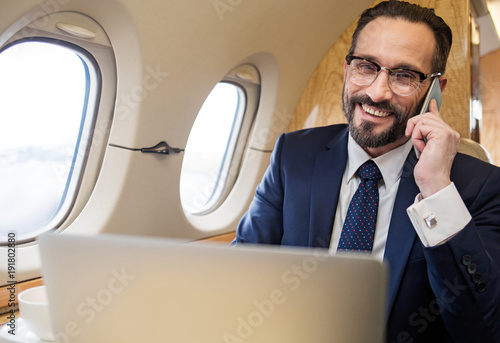 Fotografía Portrait of contented gentleman in suit chatting by cellphone during his first c
