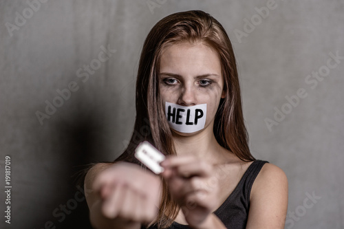Cuadros en Lienzo Teen girl cuts veins on a hand with a mouth taped with the inscription help