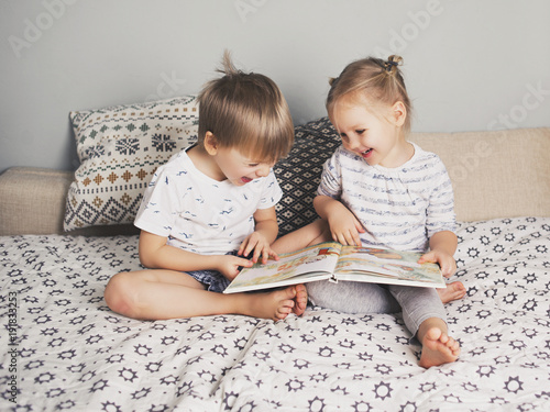 Fotomural Two kids sitting on bed and reading a book