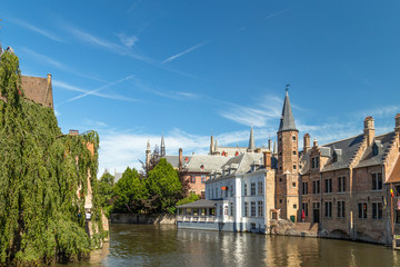 Wall Mural - The Rozenhoedkaai canal in Bruges with the belfry in the background. Typical view of Bruges (Brugge), Belgium with red brick houses with triangle shaped roofs and canals.