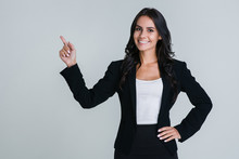 Take A Look Here! Beautiful Young Businesswoman Pointing Away And Looking At Camera With Smile While Standing Against White Background