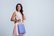 © MARIIA - Successful shopping. Beautiful young woman holding shopping bags and looking at camera with smile while standing against white background