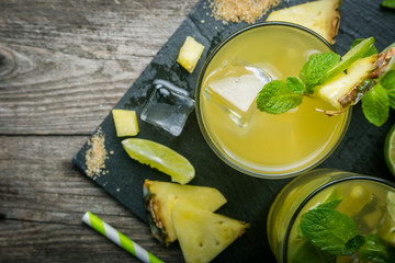 Wall Mural - Pineapple and lime drink on rustic background