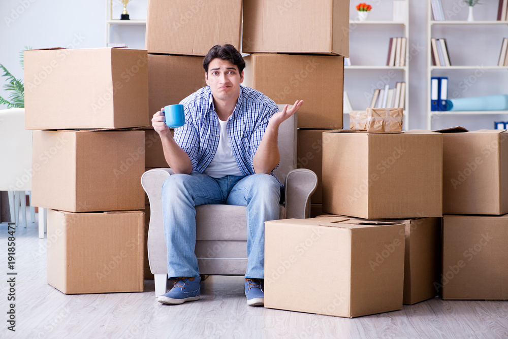 Young man moving in to new house with boxes - obrazy, fototapety, plakaty 