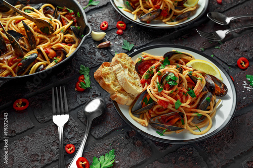 Zdjęcie XXL Domowej roboty makaronu spaghetti z mussels, pomidorowym kumberlandem, chili i pietruszką na nieociosanym tle ,. posiłek z owocami morza