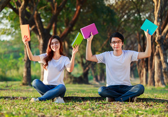 Wall Mural - couple holding a book and resting in park