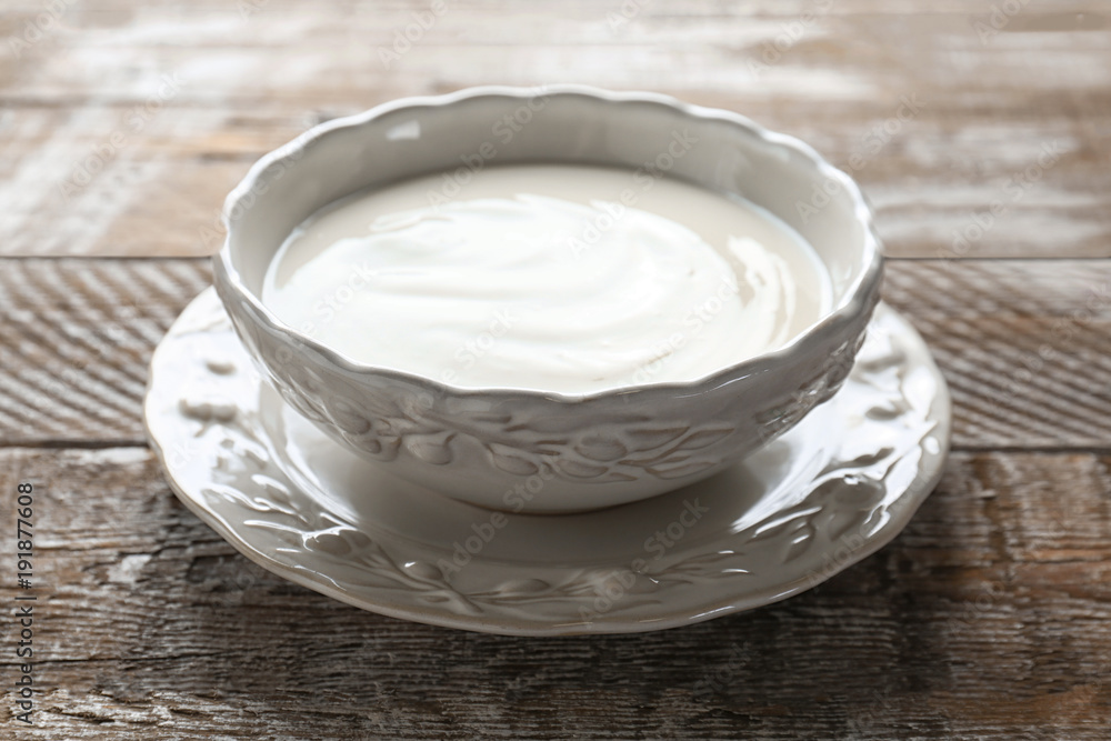 Tasty yogurt in dish on wooden table