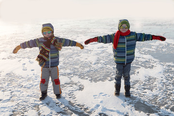 Happy boys in colorful winter clothes doing gymnastics on ice and snow. Glasses for skiing, snowboarding and sledging. A child is playing outdoors in the snow. Outdoor fun for winter holidays