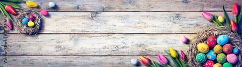 Tulips And Painted Eggs In Nests On Vintage Plank