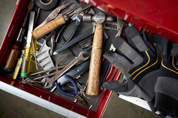 overhead view of toolbox full of tools and work gloves inside a workshop. 