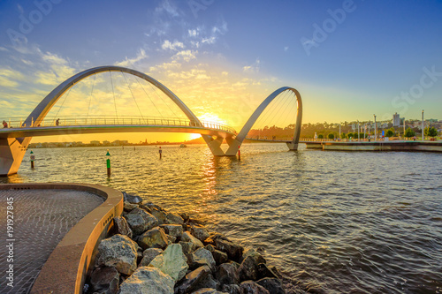 Fototapeta Sceniczny i kultowy most Elizabeth Quay o zachodzie słońca na rzece Swan przy wejściu do mariny Elizabeth Quay. Łukowy most dla pieszych to nowa atrakcja turystyczna w Perth w Australii Zachodniej.
