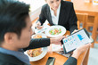 © torwaiphoto - Asian business break for lunch at a restaurant.He was watching the stock market at the table.