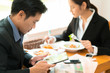 © torwaiphoto - Asian business break for lunch at a restaurant.He was watching the stock market at the table.