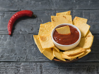 The Mexican tortilla chips with cheese and chili peppers on a rustic table.