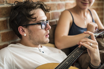 Wall Mural - Caucasian couple on the bed, man playing a guitar