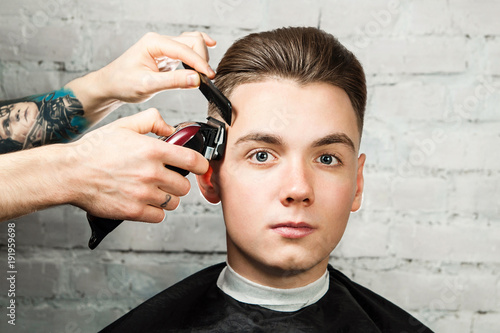 Barber Cuts Hair Of Young Guy In The Barbershop Hairdresser