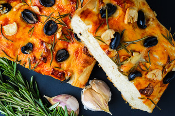 Traditional Italian vegetarian focaccia of homemade bread with olives, rosemary and garlic