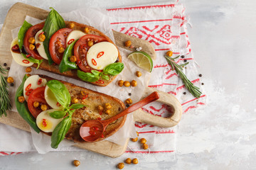 Wall Mural - Caprese sandwich with mozzarella, tomato, fried chickpeas and basil on a wooden board, top view, copy space. Italian cuisine concept.