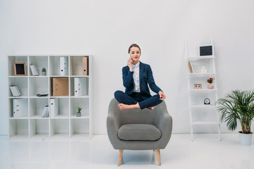 Wall Mural - young businesswoman talking by smartphone and smiling at camera while levitating in office