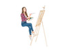© LIGHTFIELD STUDIOS - young woman levitating and painting on easel isolated on white