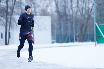 Photo of running athlete in black clothes at stadium