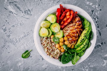 Vegetable bowl lunch with grilled chicken and quinoa, spinach, avocado, brussels sprouts, paprika and chickpea