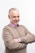 © Viacheslav Yakobchuk - Confident man. Pleasant grey-haired senior man in a sweater on top of a lilac shirt folding his arms across his chest and posing isolated on a white background