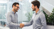 Two smiling businessmen shaking hands together while standing in modern office.