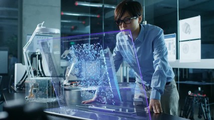 Asian Neural Network Engineer Uses Modern Computer With Transparent Holographic Display. Monitor Shows Interactive Artificial Intelligence Interface . Shot in Modern Glass and Concrete Office.