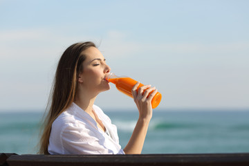 Wall Mural - Woman drinking an orange juice on the beach