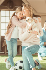 Wall Mural - smiling mother and daughter playing with adorable labrador puppy