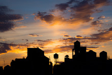 Silhouetted Rooftops And Water Towers At Sunset