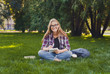 © Prostock-studio - Young woman sitting with notebook on grass