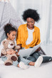 © LIGHTFIELD STUDIOS - african american mother and daughter reading book on floor at home