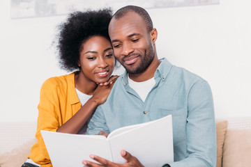 Wall Mural - african american couple reading book together at home