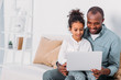 © LIGHTFIELD STUDIOS - happy african american father and daughter using laptop at home