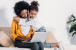 © LIGHTFIELD STUDIOS - african american mother and daughter watching something on laptop at home