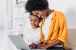 © LIGHTFIELD STUDIOS - african american mother and daughter looking at laptop at home