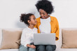 © LIGHTFIELD STUDIOS - african american mother and daughter with laptop on sofa at home