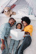 © LIGHTFIELD STUDIOS - high angle view of african american parents and daughter lying on floor and reading book