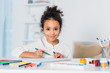 © LIGHTFIELD STUDIOS - adorable african american kid drawing with felt pens and looking at camera at home