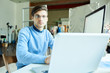 © Seventyfour - Portrait of young office worker wearing glasses using PC sitting at desk in modern office, copy space