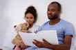 © LIGHTFIELD STUDIOS - african american father reading book for daughter at home