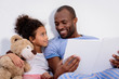 © LIGHTFIELD STUDIOS - african american father holding book and looking at daughter at home