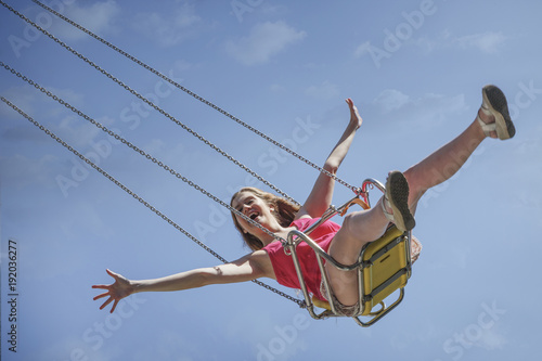 Smiling Caucasian Woman Riding Swing On Amusement Park Ride