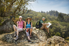 Hikers Resting On Rocks And Reading Map