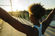 © Inti St Clair/Blend Images - Mixed Race woman wearing earbuds stretching arms on bridge