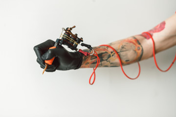 Wall Mural - Man's hand holding tattoo machine on white background. the red wires