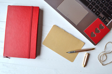 Wall Mural - Red sketchbook, laptop, pen and empty sheet on the white wooden desk. Top view. Business workplace.