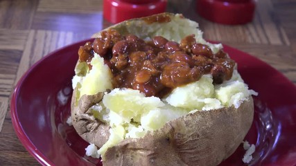 Canvas Print - Topping a baked potato with chili and cheese
